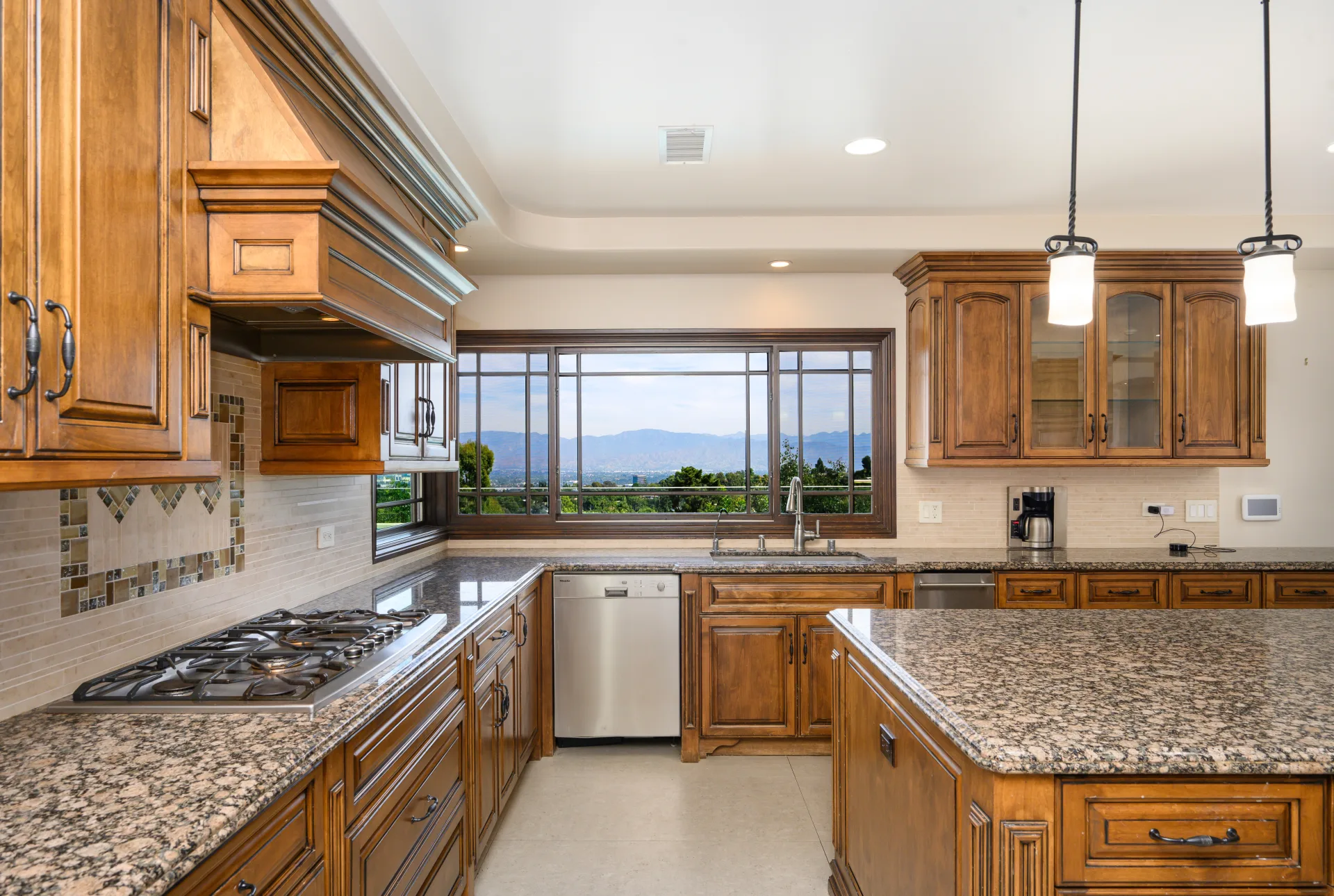 A kitchen with wood cabinets and granite counters, looking out over the Colorado foothills