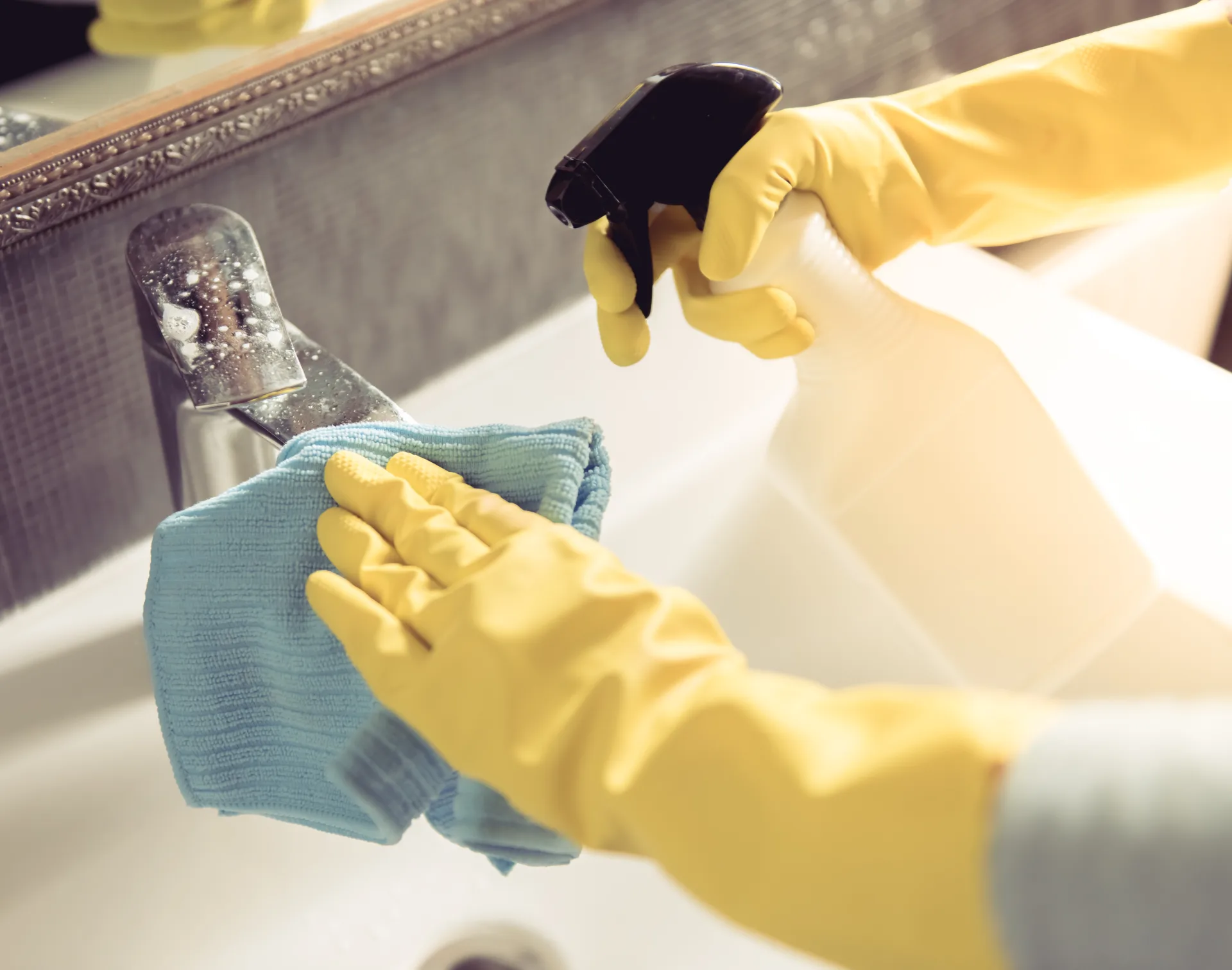 Cleaning a bathroom tap with spray and a cloth