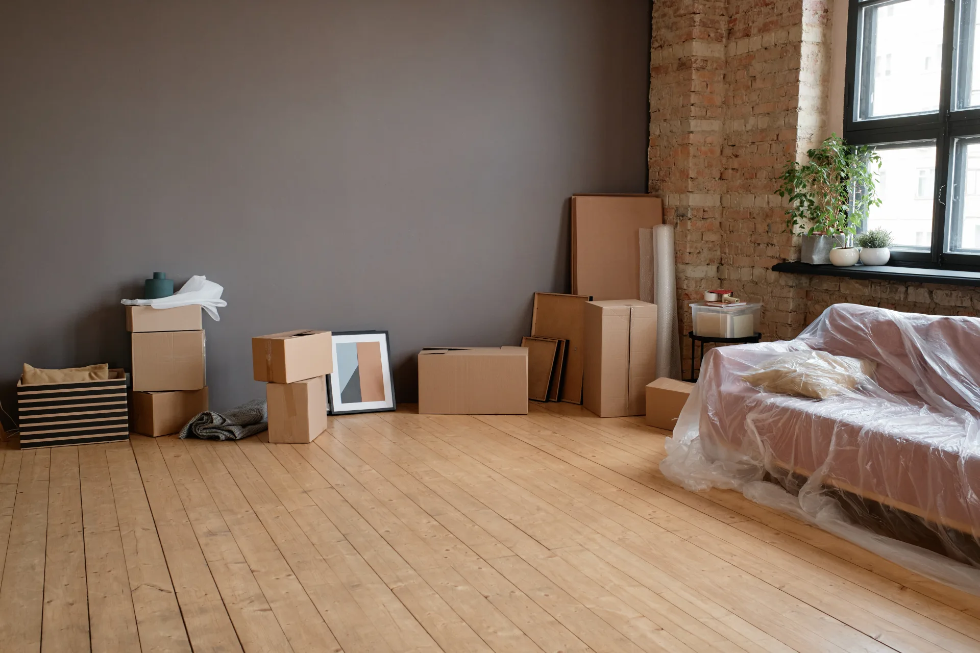 An almost empty room with a bare wood floor and a few packing boxes left along the wall